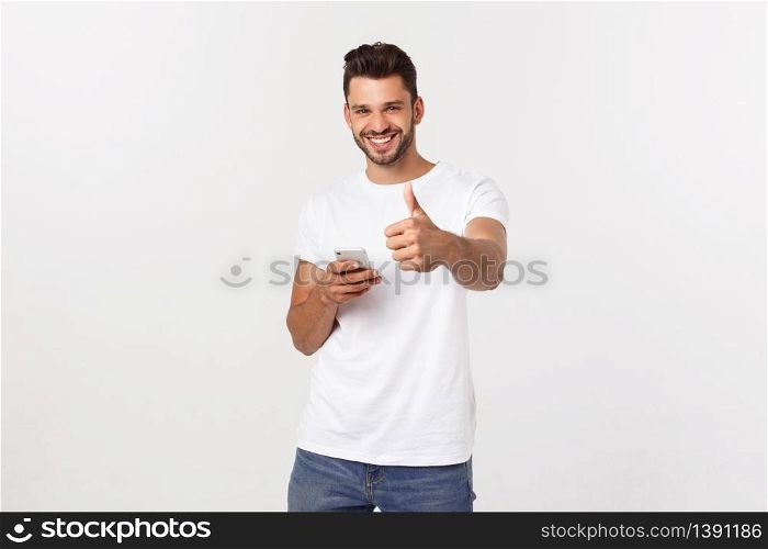 Happy casual man with smartphone and thumb up over gray background.. Happy casual man with smartphone and thumb up over gray background
