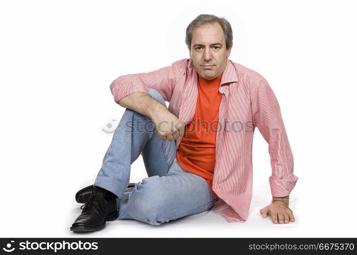 happy casual mature man seated on the floor, studio picture. mature man seated