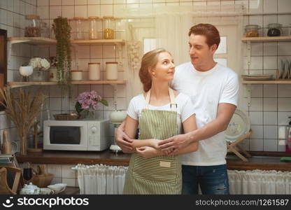Happy caucasian couple hugging in the kitchen at home.