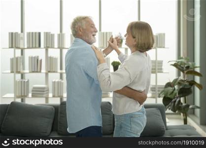 Happy Caucasian senior couple dancing at home