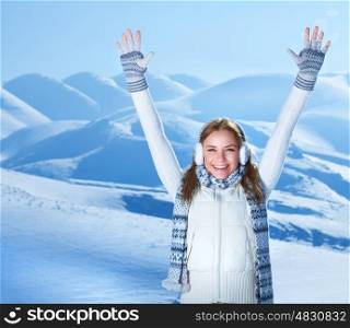 Happy cheerful girl with raised up hands enjoying snowy winter weather, with pleasure spending Christmas holidays in the mountains