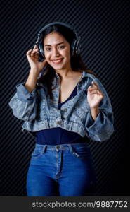 Happy cheerful pretty smiling of portrait of young Asian woman vocalist Wearing Headphones recording a song in a professional studio