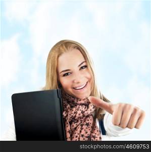Happy cheerful student outdoor, pretty casual college pupil, closeup on cute young girl smiling, blond teen female model over blue sky, woman holding laptop, studying, thumbs up, success concept