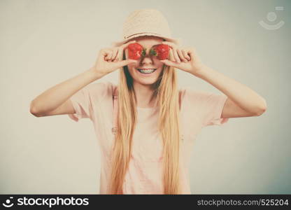 Happy cheerful teenage young woman ready for summer wearing pink outfit and sun hat holding sweet fruit red strawberries. Happy woman holding strawberries