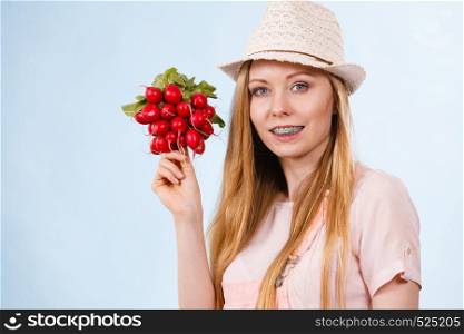 Happy cheerful teenage young woman ready for summer wearing pink outfit and sun hat holding delicious radish. Happy woman holding radish