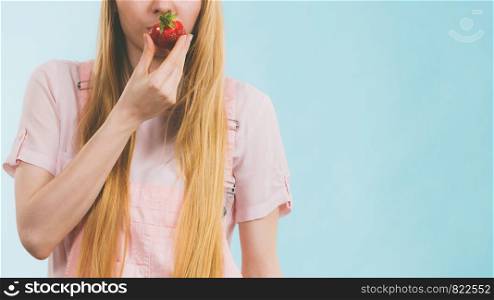 Happy cheerful teenage young woman ready for summer wearing pink outfit and sun hat holding sweet fruit red strawberries. Happy woman holding strawberries