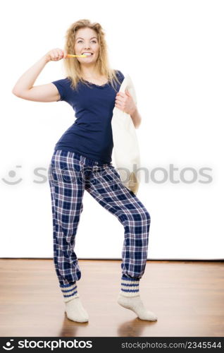 Happy cheerful woman wearing blue pajamas holding pillow and toothbrush, sleep outfit blue tshirt and checked trousers. Happy cheerful woman wearing pajamas