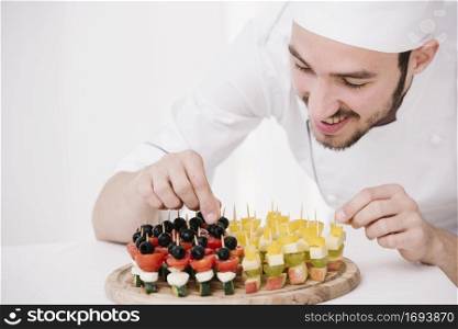 happy chef arranging snacks wooden board