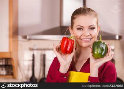 Happy chef woman holding two bell peppers, red and green. Healthy lifestyle, eating vegetables, vegetarian food concept.. Woman holding two bell peppers