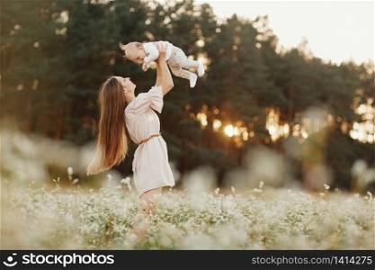 Happy child and his mom have fun outdoors in a field. Mom holds the child in her arms, and the child hugs. Mother&rsquo;s Day. selective focus.. Happy child and his mom have fun outdoors in a field. Mom holds the child in her arms, and the child hugs. Mother&rsquo;s Day. selective focus