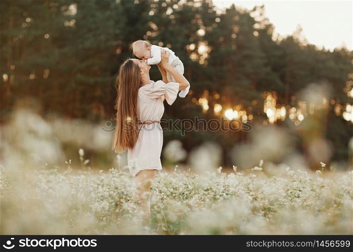 Happy child and his mom have fun outdoors in a field. Mom holds the child in her arms, and the child hugs. Mother&rsquo;s Day. selective focus.. Happy child and his mom have fun outdoors in a field. Mom holds the child in her arms, and the child hugs. Mother&rsquo;s Day. selective focus