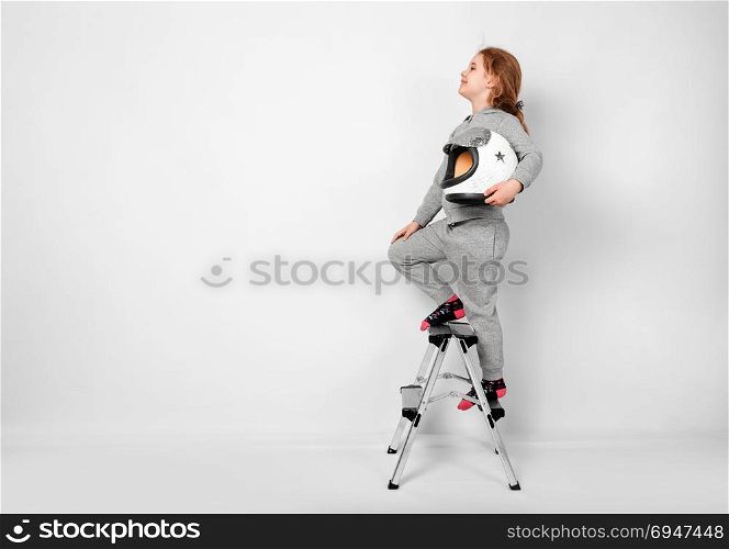 Happy child girl dressed in an astronaut costume standing on stepladder. Happy child girl dressed in an astronaut costume standing on stepladder.