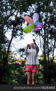 Happy child girl playing with colorful toy balloons in the park outdoors.