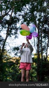 Happy child girl playing with colorful toy balloons in the park outdoors.