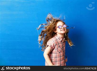 Happy child girl tourist in pink sunglasses at the blue wall. Travel and adventure concept. Happy child girl tourist in pink sunglasses at the blue wall. Travel and adventure concept.