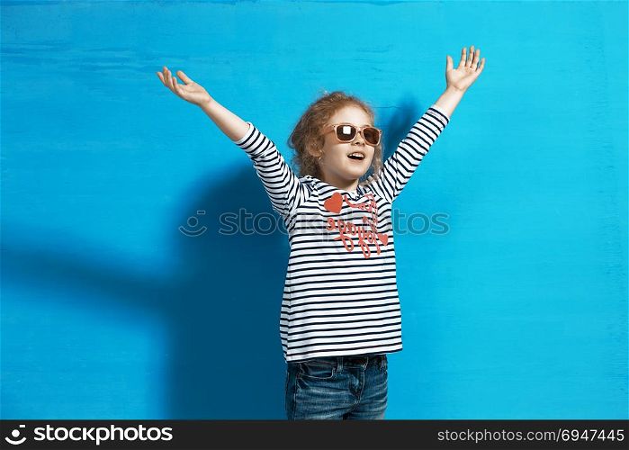 Happy child girl tourist in pink sunglasses at the blue wall. Travel and adventure concept. Happy child girl tourist in pink sunglasses at the blue wall. Travel and adventure concept.