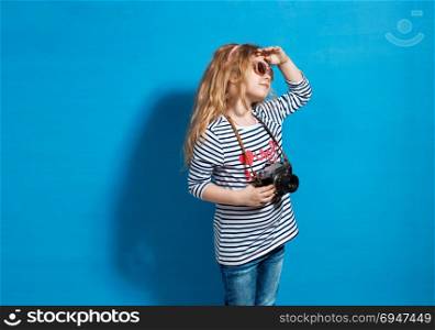 Happy child girl tourist with retro camera at the blue wall. Happy child girl tourist with retro camera at the blue wall.