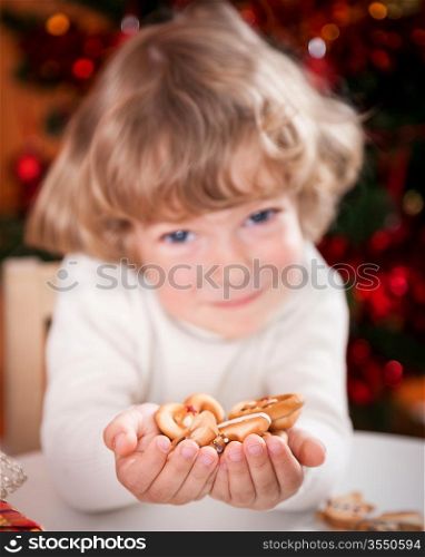 Happy child holding cookies against Christmas lights background