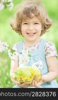 Happy child holding Easter eggs in hands against spring green background