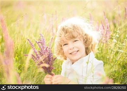 Happy child holding spring flowers in hands outdoors