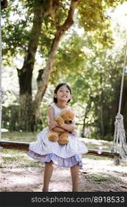 Happy Child hug teddy bear in green park playground. Teddy bear best friend for little kids cute girl. Autism happy funny playing together on playground in happiness family feel love and warm hugs