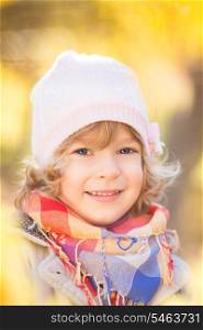 Happy child in autumn park against yellow blurred leaves background
