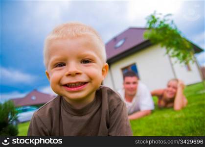Happy child in front of the house with parents in the background