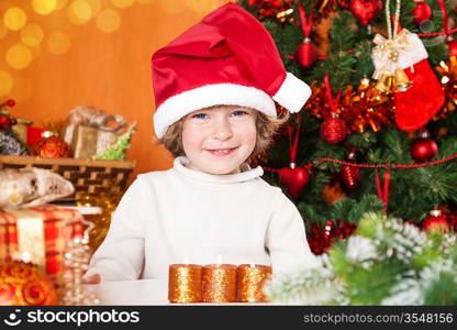 Happy child in Santa`s hat against Christmas tree with decorations