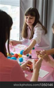 Happy child paints Easter eggs with his family