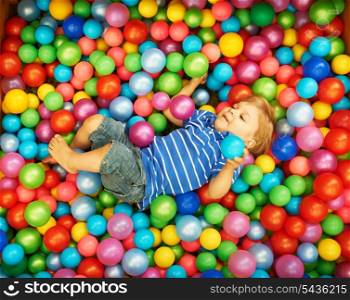 Happy child playing at colorful plastic balls playground high view