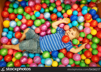 Happy child playing at colorful plastic balls playground high view