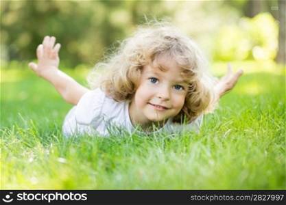Happy child playing on green grass in spring