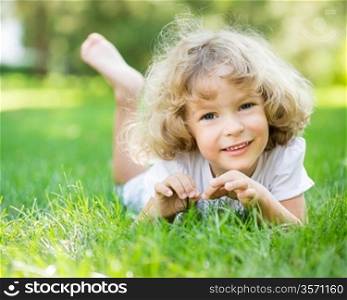 Happy child playing on green grass in spring park