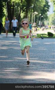 Happy child running in city park. Positive childish emitions. Child running along path smiling and rejoicing. Happy childhood. Little girl enjoying run. Happy child running in city park. Little girl enjoying run