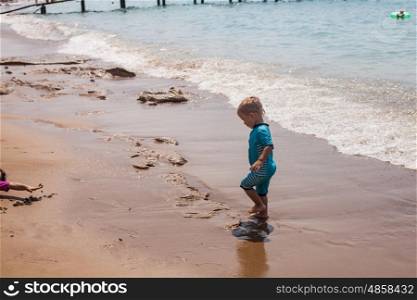 Happy child walking on summer beach. Holidays with kids.. Little boy runs to the sea