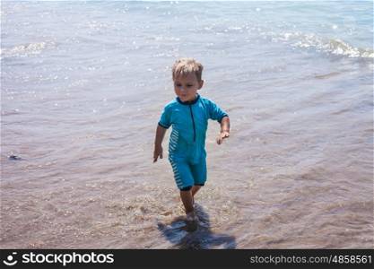 Happy child walking on summer beach. Holidays with kids.. Little boy runs to the sea