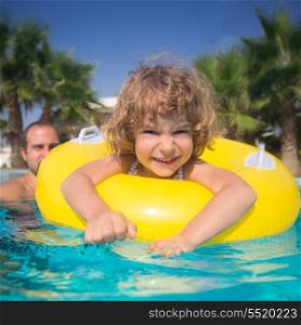 Happy child with father playing in swimming pool. Summer vacations concept
