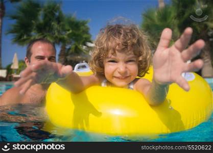 Happy child with father playing in swimming pool. Summer vacations concept