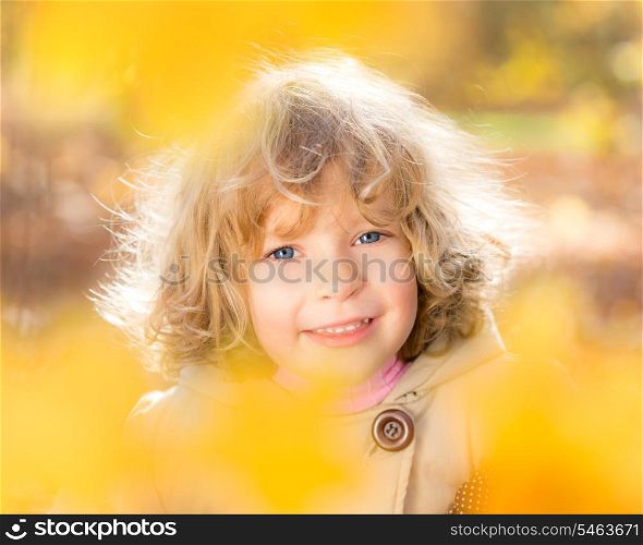 Happy child with maple leaves in autumn park