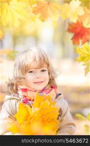Happy child with maple leaves in autumn park