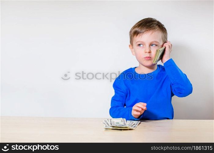 Happy child with money dollar, little businessman. Pile of United States dollar hundred USD banknotes in boy&rsquo;s hand.. Happy child with money dollar, little businessman. Pile of United States dollar hundred USD banknotes