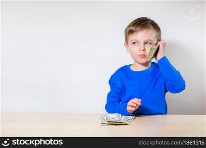 Happy child with money dollar, little businessman. Pile of United States dollar hundred USD banknotes in boy&rsquo;s hand.. Happy child with money dollar, little businessman. Pile of United States dollar hundred USD banknotes