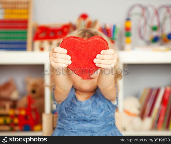 Happy child with small handmade paper red heart in class. Valentine`s day concept