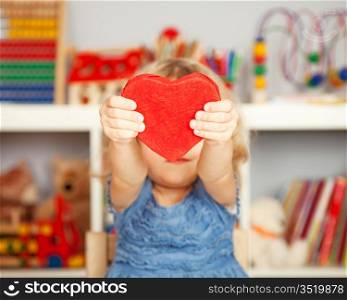 Happy child with small handmade paper red heart in class. Valentine`s day concept