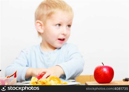 Happy childhood. Boy child kid preschooler eating peeled apple fruit or making batter for drop scones. At home.