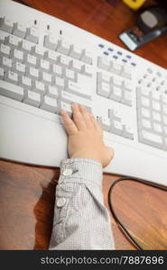 Happy childhood. Closeup of hand of smart little boy child kid on the computer keyboard at home. Technology.