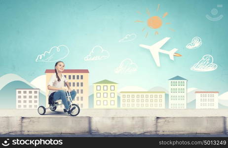 Happy childhood. Cute girl against drawn background riding three wheeled bike