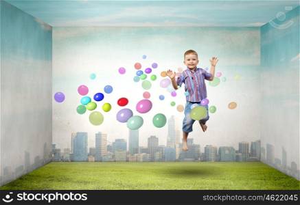 Happy childhood. Little cute boy in jump and colorful balloons around