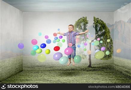 Happy childhood. Little cute boy in jump and colorful balloons around
