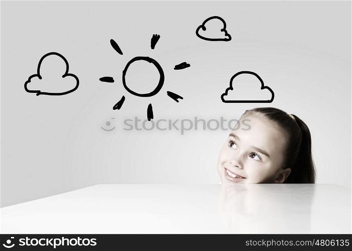 Happy childhood. Little cute girl looking at drawing of sun